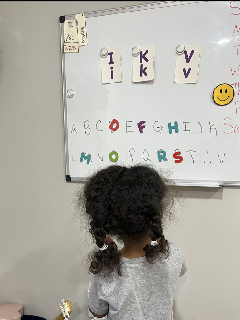 little girl matching letters to white board